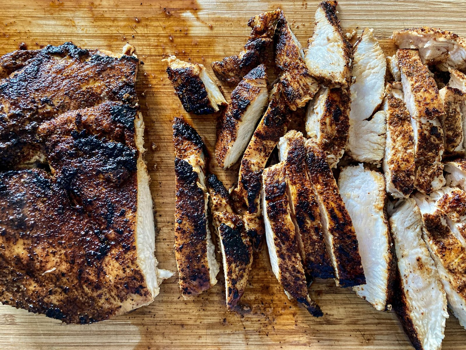 a wooden cutting board topped with sliced up meat