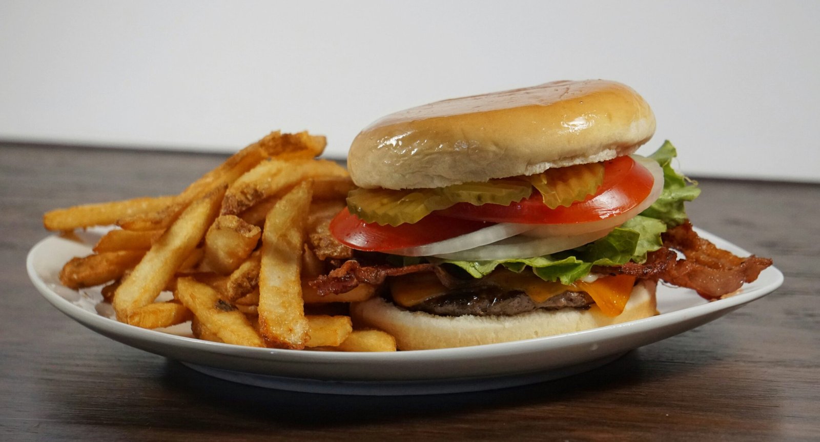 burger with tomato and lettuce on white ceramic plate