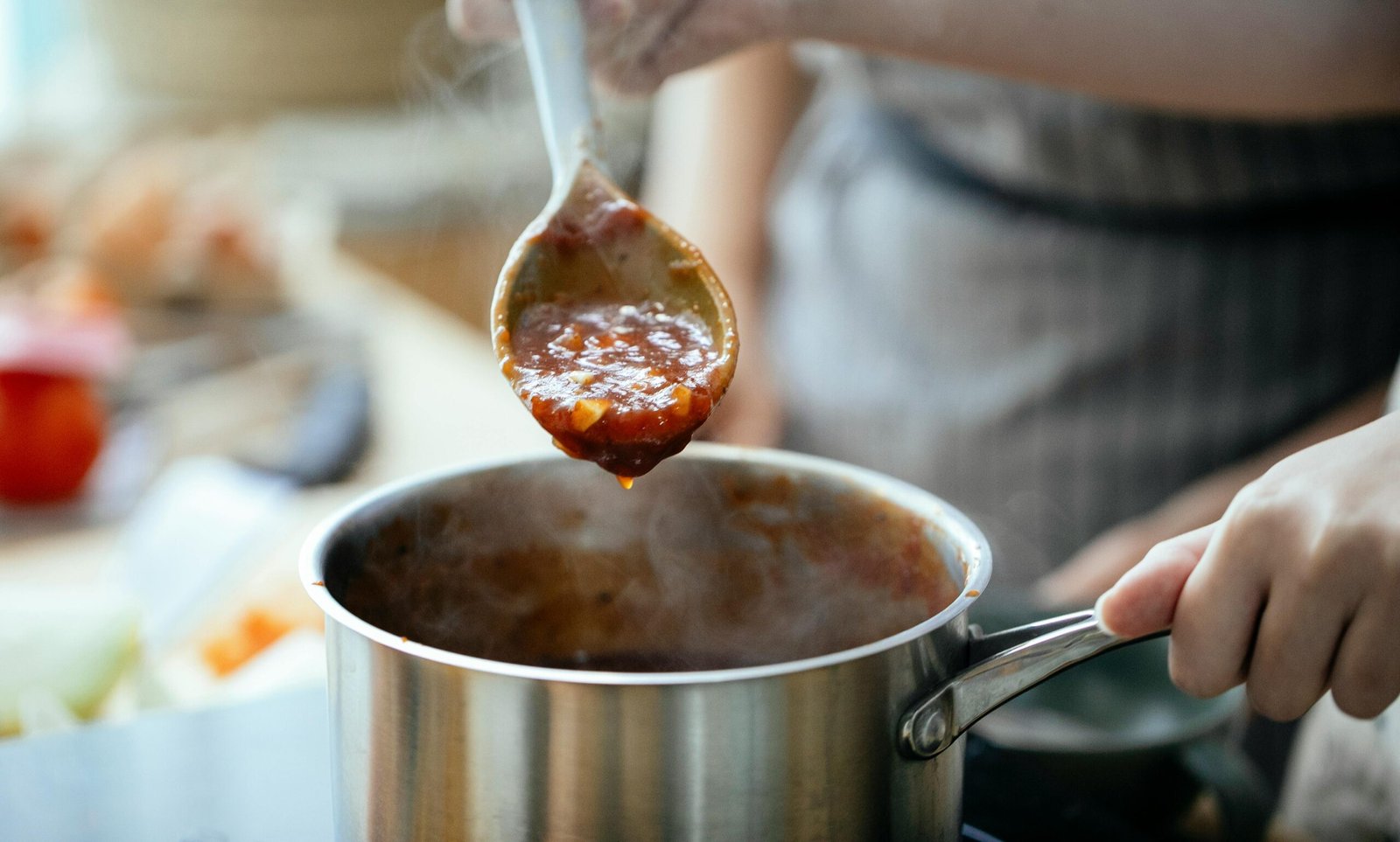 Crop women cooking sauce together